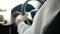 Young woman driving a car, hand put on the black steering wheel and looking forward with determination.