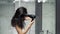 Young woman is drying her hair with a hairdryer and is shocked by the large amount of hair loss