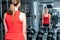 Young woman with dumbbells in front of a mirror in the gym. Beautiful woman doing sports with dumbbells
