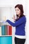 Young woman dusting a bookcase