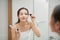 Young woman dyes her eyelashes with mascara brush. Young beautiful woman applying mascara makeup on eyes at bathroom