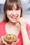 Young Woman Eating Bowl Of Healthy Seeds