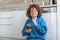 Young woman eating chocolate from a jar while sitting on the wooden kitchen floor. Cute ginger girl indulging cheeky face eating