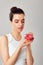 Young woman eating donut over grey background. Brunette girl tastes a donut. Diet. Health care.