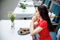 Young woman eating healthy food sitting oudoors at the cafe terrace alone. Girl wearing in red polka dot dress