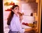 Young woman eating junk croissant near fridge in night