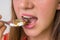 Young woman eating pills on a spoon