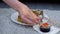 Young woman is eating sushi rolls in living room on floor, hands closeup.