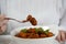 Young woman is eating traditional homemade Hungarian beef meat stew and soup - Goulash