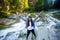 Young woman on edge of rock near fast river in middle of forest.