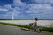 young woman electric green bike bicycle by windmill farm , windmills  on a beautiful bright day Netherlands