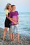 Young woman embraces smiling boy on beach