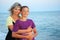 Young woman embraces smiling boy on beach