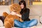 Young woman embracing teddy bear sitting on sofa