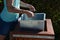 Young woman emptying a trash can in the park. it is her job or a summer job in a municipal gardening company serving citizens. hol