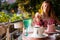 Young woman enjoying a cup of Turkish coffee served outside with water flowers and delight dessert in romantic setup on glass