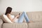 Young woman enjoying interesting book sitting on couch, reading