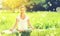 young woman enjoying meditation and yoga on green grass in summer on nature