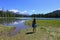 Young woman enjoying view of Sisters volcanoes reflected in Scott Lake, Oregon.