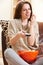 Young Woman Enjoying Watching TV Whilst Eating Popcorn