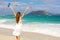 Young woman enjoying wind with raised arms and people kitesurfering, Corralejo Dunes beach, Fuerteventura, Canary Islands