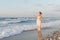 Young woman enjoys a lonesome walk on the beach at dusk.