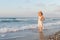 Young woman enjoys a lonesome walk on the beach at dusk.