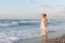 Young woman enjoys a lonesome walk on the beach at dusk.