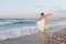 Young woman enjoys a lonesome walk on the beach at dusk.