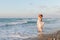 Young woman enjoys a lonesome walk on the beach at dusk.