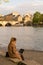 A young woman enjoys working on her computer sitting on the banks of the Seine in Paris, by a spring sun