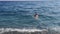 A young woman enters the sea and floats on a wave. Video 9 seconds