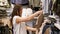 Young woman examines a beige dress made of coarse cotton fabric in a store