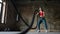 Young woman exercising with battle ropes at the gym. Strong female athlete doing crossfit workout with battle rope