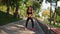 Young woman exercising, doing squats in the park listening to the music. Morning sport. Slowmotion shot