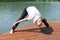 Young woman is exercising on the pier at the lake. active sports lifestyle. outdoor gymnastics.