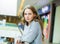 Young woman with face with freckles is standing in supermarket.