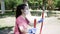 Young woman in face mask, gloves, goes sports in outdoor exercise equipment Park