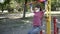 Young woman in face mask, gloves, goes sports in outdoor exercise equipment Park