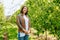 Young woman farmer calm smile stands with hands clasped in castle apple orchard looking at camera.