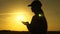 Young woman farmer works with tablet on a wheat field in the sun. silhouette of female agronomist with tablet studying