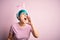 Young woman with fashion blue hair wearing easter rabbit ears over pink background shouting and screaming loud to side with hand