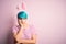 Young woman with fashion blue hair wearing easter rabbit ears over pink background thinking looking tired and bored with