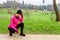 Young woman feeling lightheaded or with headache after train on a cold winter day on the training track of an urban park.