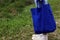 Young woman feet standing on grass holding a blue women foldable shopping bag reusable eco. Love nature and earth concept.