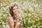 Young woman in a field of blooming daisies