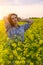 Young woman in a field of oil rapeseed in bloom in sunset. Freedom and ecology concept.