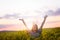 Young woman in a field of oil rapeseed in bloom in sunset. Freedom and ecology concept.