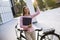 Young woman with files in the hands standing outdoor next to electric bike