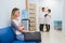 Young woman filling nervous sitting at hospital corridor waiting while two doctors talking on a backgroud